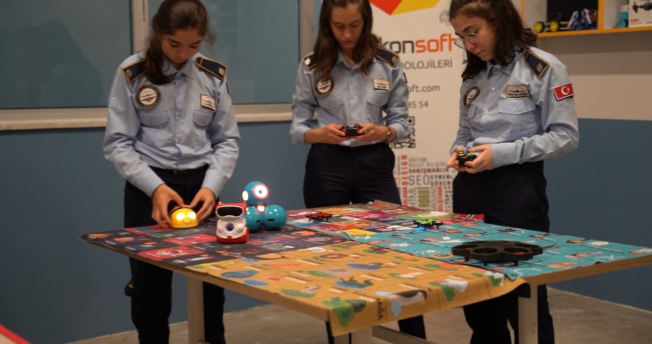 Üniformalı öğrenciler robotik kodlama atölyesinde robotları programlıyor